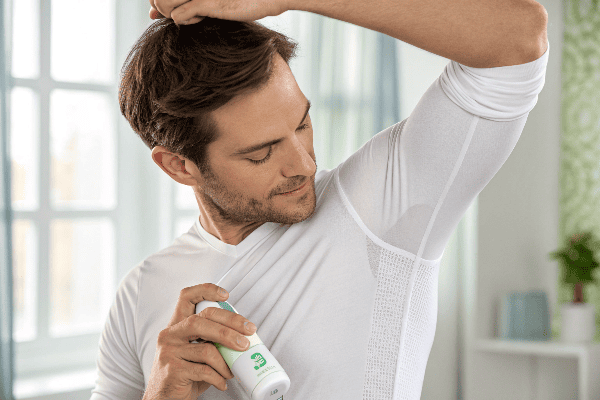 Person applying antiperspirant with protective undershirt